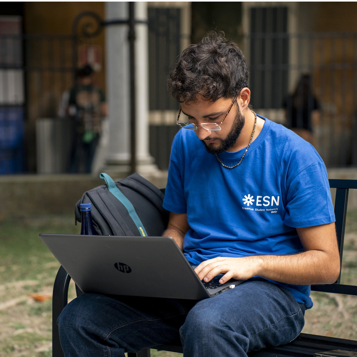 Image of a person outside typing on a laptop.