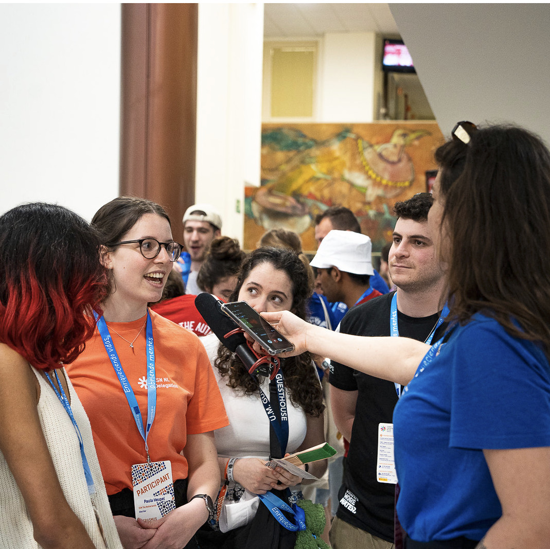 Image of someone being interviewed at an event, with people around.
